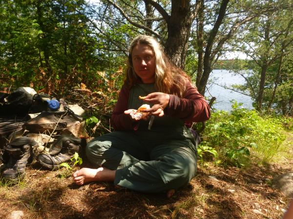 Gillian in the Boundary Waters with food in front of tre