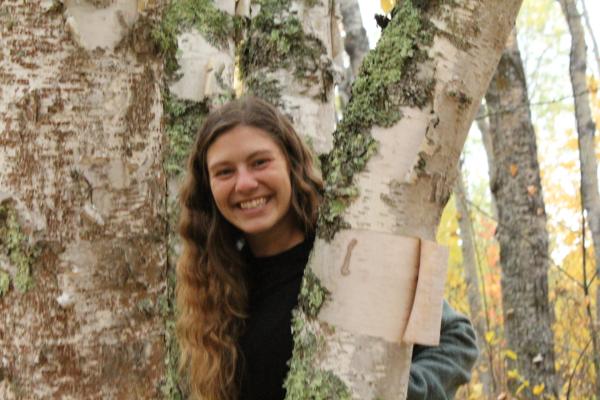 Lucy Trotter peaking out behind tree. 