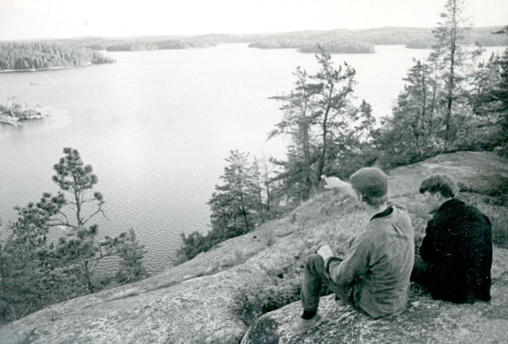 Two men on rock looking at lake