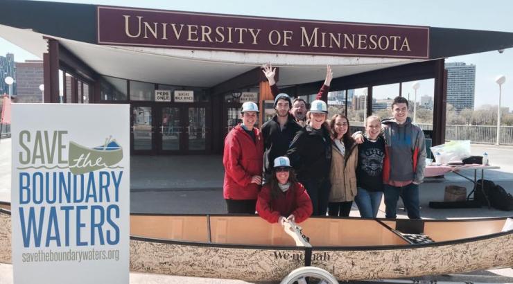 Group of people standing behind a signature canoe at the University of Minnesota