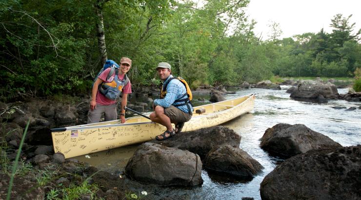 photo of Dave and Amy Freeman squatting next to a canoe on some rocks in the Boundary Waters