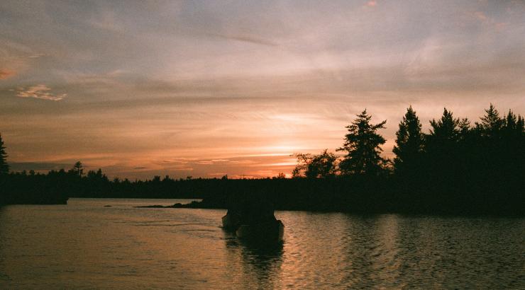 Silhouette of people canoeing into the sunset 