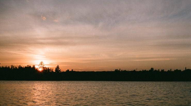 photo of Boundary Waters Sunset with orange and blue sky over tree silhouettes on horizon