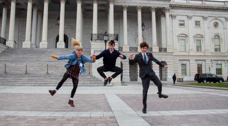 Photo of 3 kids jumping up and clicking their heels infront of a building in Washington DC