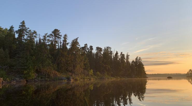 Photo of Boundary Waters sunrise with trees reflecting on calm water