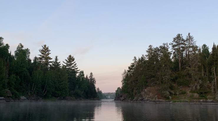 photo of a chanel of water going between 2 islands with trees reflecting on calm water