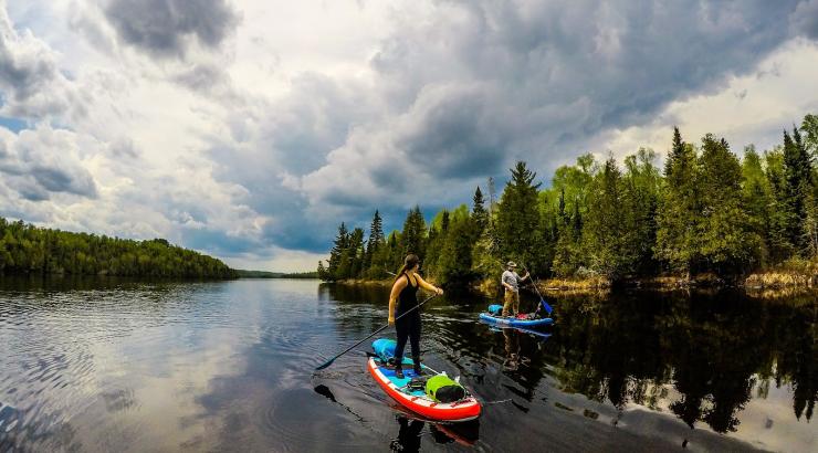 Image of 2 people paddle boarding through channel in Boundary Waters