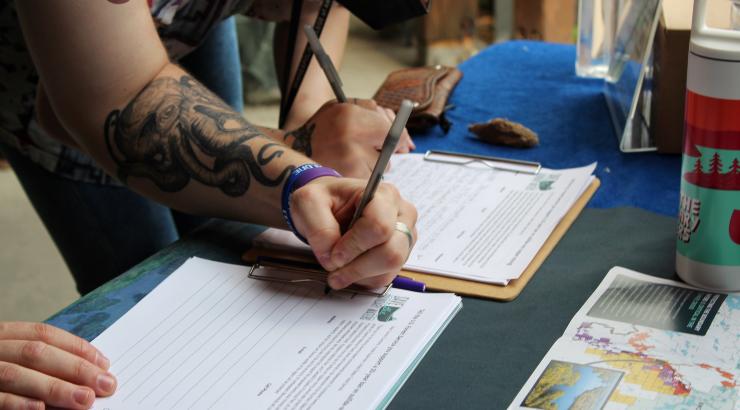 A close-up image of a hand signing a petition in support of a recommended 20-year ban on sulfide-ore copper mining near the Boundary Waters at a recent Save the Boundary Waters event 