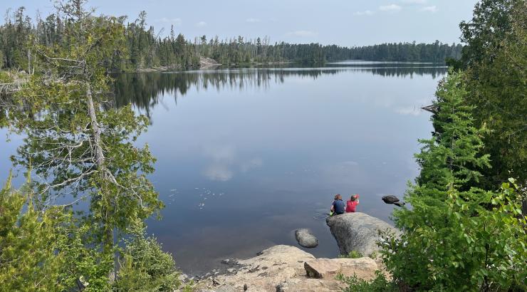 Kids sitting down by the water in the Wilderness