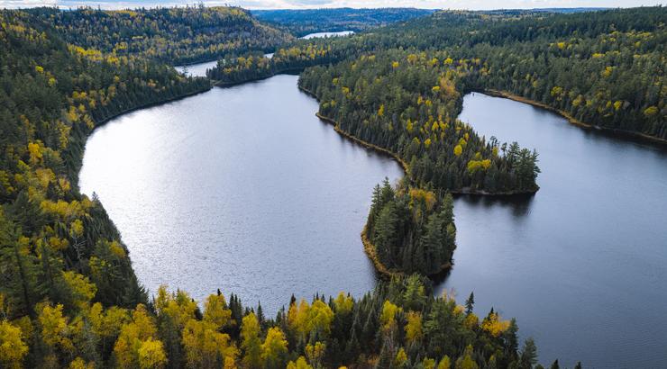 An aerial view of a few Boundary Waters lakes surrounded by autumn woods.