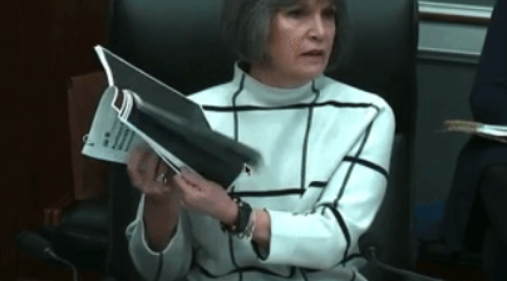 Photo of Rep. McCollum holding up blacked out pages