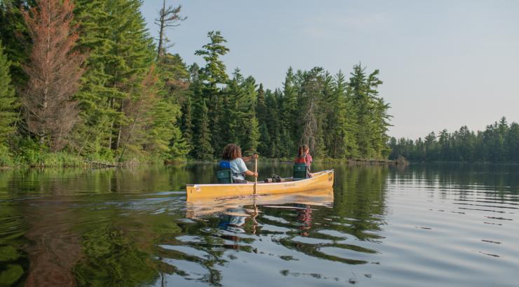 Two girls paddling in the Boundary Waters in a yellow canoe