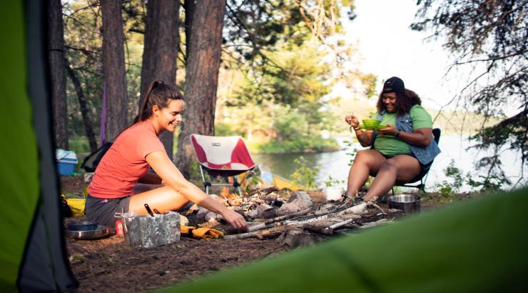 two people sitting at campsite around fire pit in daylight