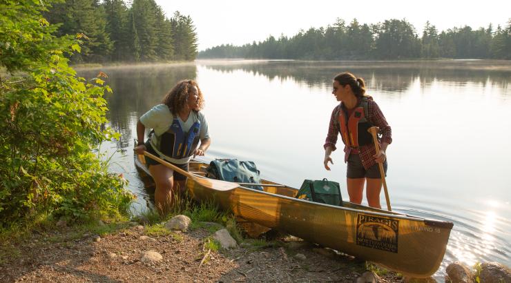 two people getting into a canoe on shore