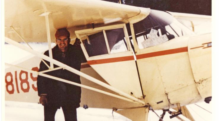 Photo of Bill Rom standing under an old school plane