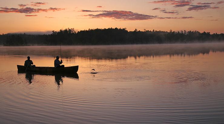 silhouette of 2 people in a canoe at sunset