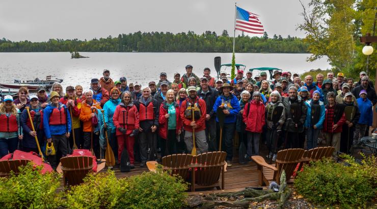 Large group of supporters holding up paddles standing near Boundary Waters