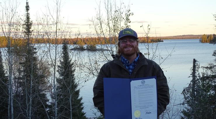 photo of a man holding the Boundary Waters proclamation infront of a snowy boundary waters