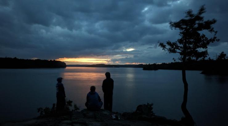 Urban Boatbuilders Apprenticeship participants at their campsite on a cloudy evening in the BWCA