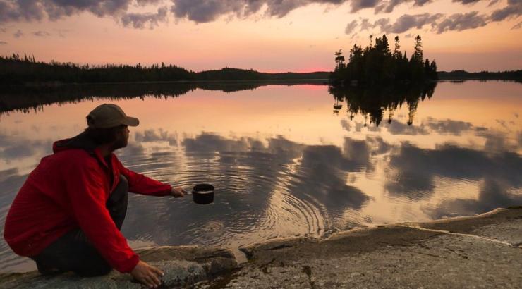 Dave Freeman dipping pot into lake at sunset