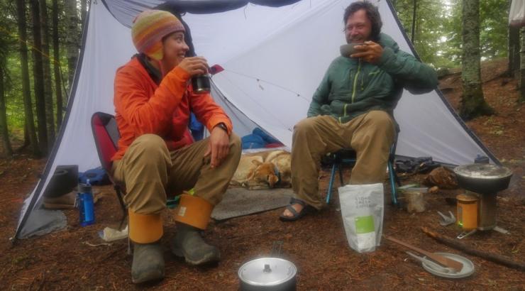 Photo of Amy and Dave Freeman sitting on chairs under a tent eating a camp meal