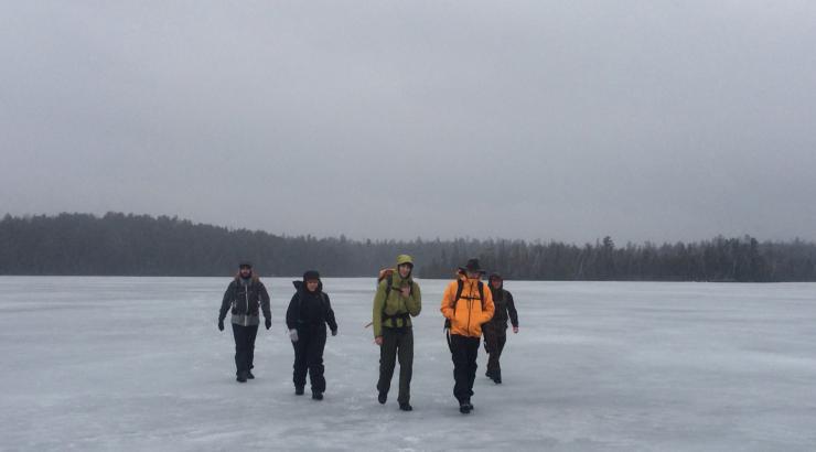 Photo of 5 people walking on frozen lake in Boundary Waters