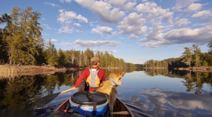 Photo of Amy Freeman canoeing with a dog sitting behind her in the boat