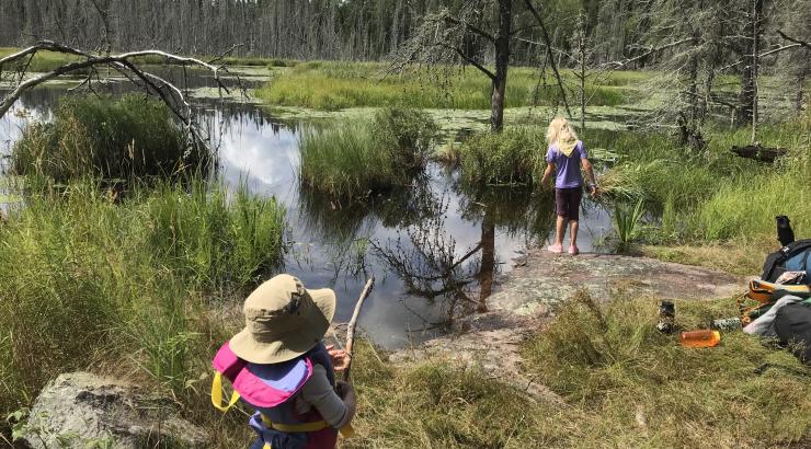 pictures of two kids standing on the shore next to a lake