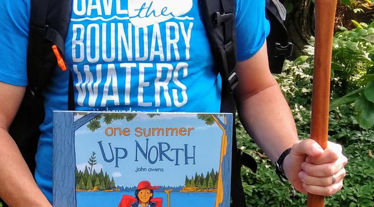 photo of a person holding a canoe paddle and a childrens book reading "one summer up north"
