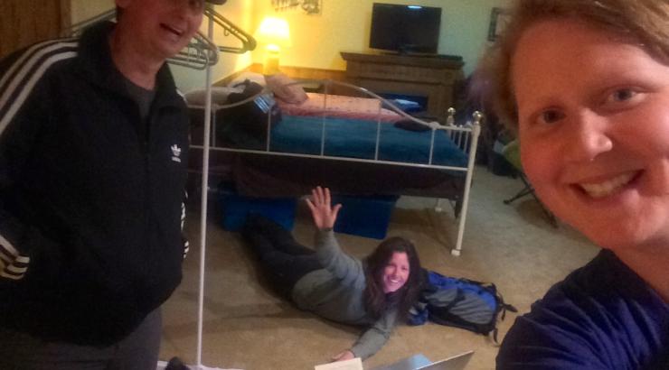 Photo of 2 people smilimg selfie style and one person lying on the floor smiling