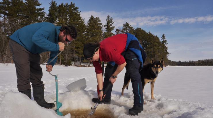 Photo of Amy and Dave Freeman leaning over an ice hole in a frozen lake
