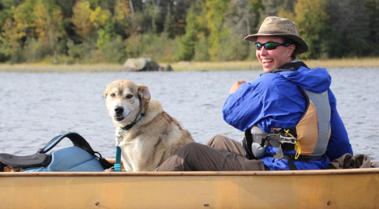 Photo of Amy Freeman paddling a canoe with a sled dog on the South Kawishiwi River