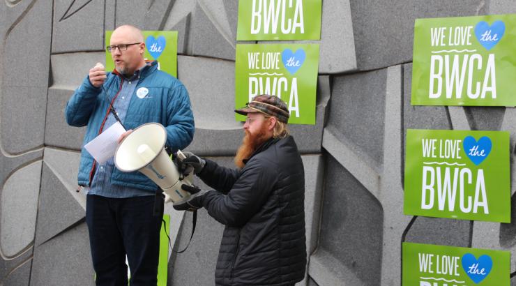 Photo of 2 men standing infront of We love the BWCA signs holding a mega phone