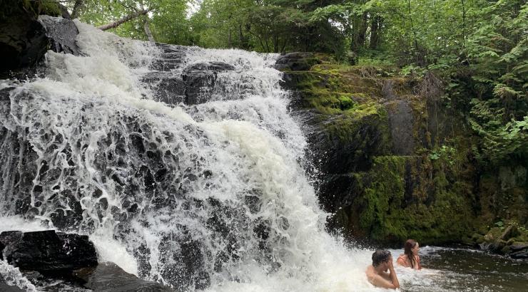 Photo of 2 people swimming in a waterfall