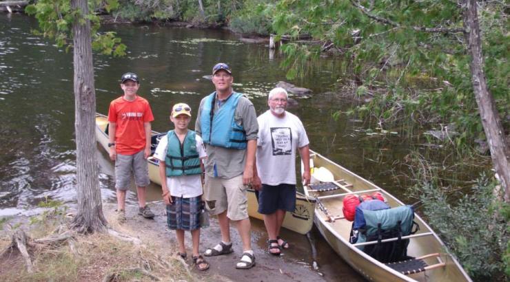 Group of people standing next to a canoe