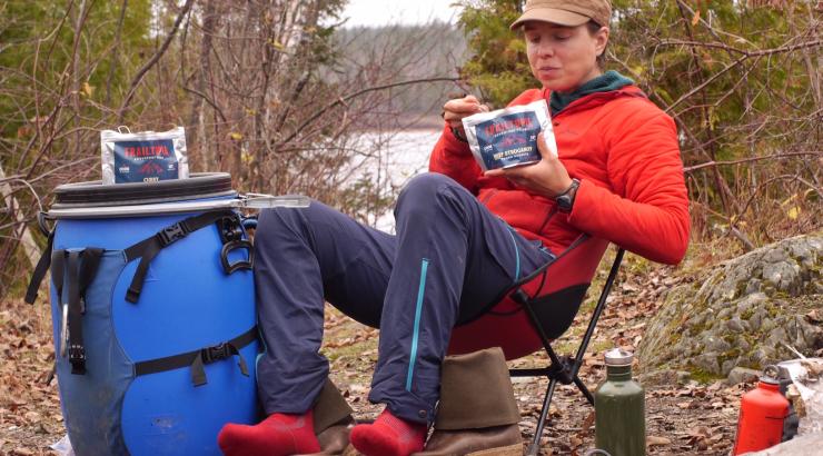 Amy Freeman sitting on a camp chair eating a trail meal