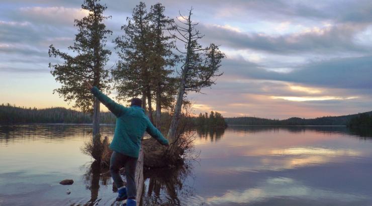 Photo of person walking on a log towards an island in the Boundary Waters