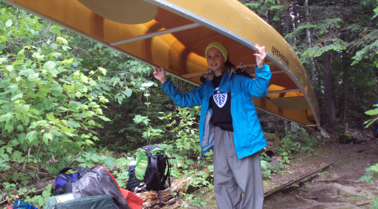 Photo of Grace Christenson portaging a canoe