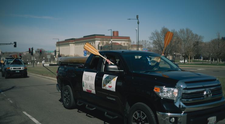 Image of truck driving by with people holding canoe paddles out windows