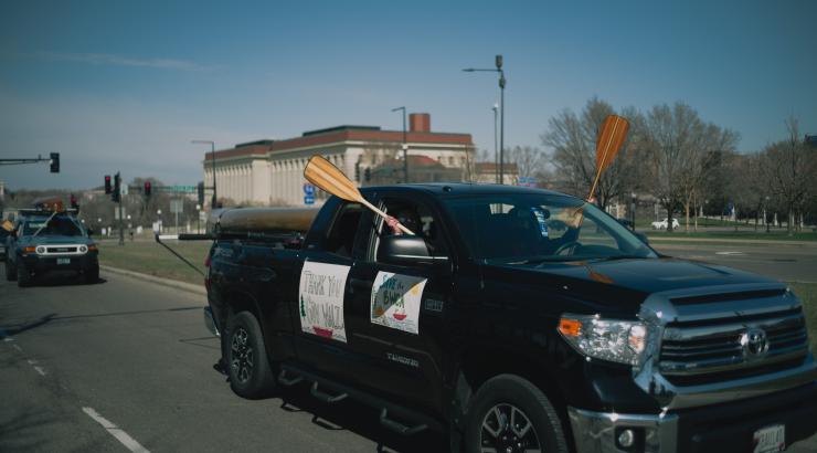 Image of truck driving by with people holding canoe paddles out windows