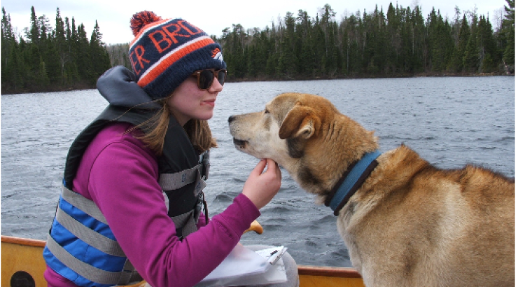 Photo of woman face to face with a sled dog in a canoe