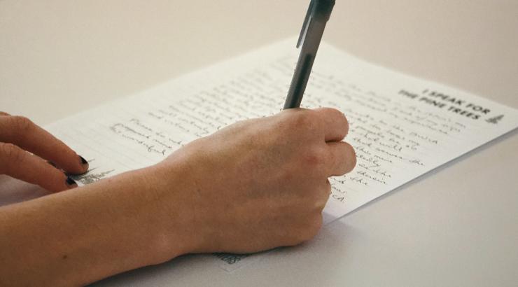 person holding pen over paper