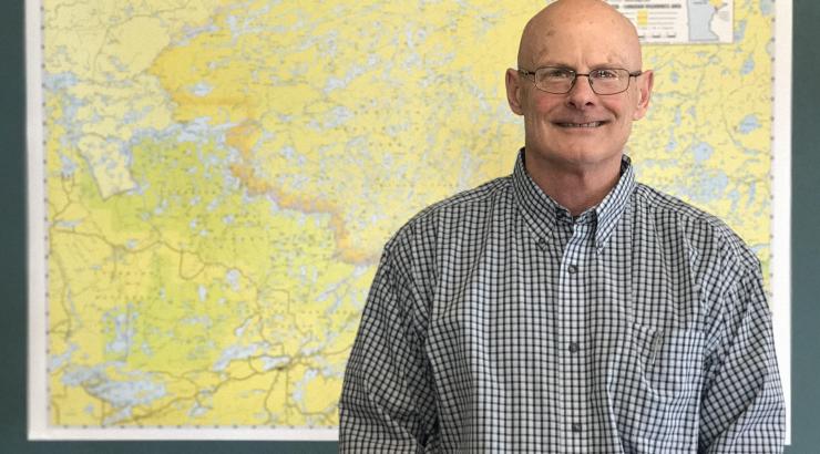 Photo of Executive Director Tom Landwehr standing infront of yellow map