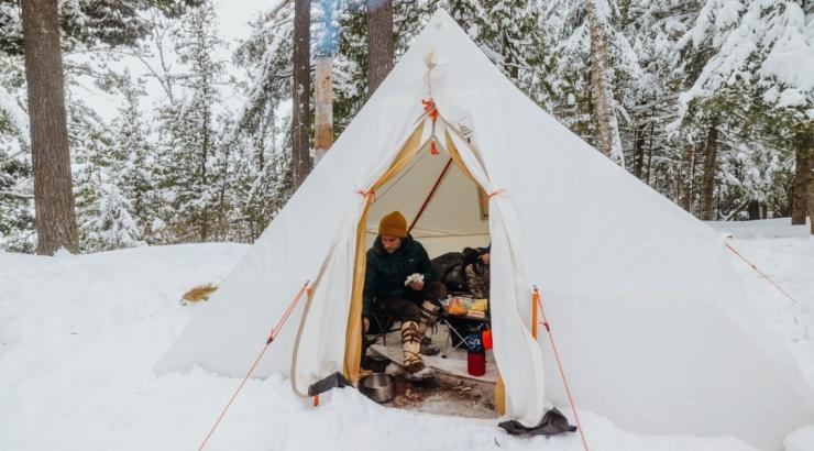 Person inside a white winter camping tent. Photo: Nate Ptacek