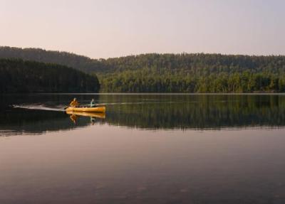 Two people paddle on a quiet lake in the Wilderness.