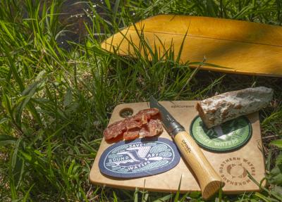 Cutting board display with assorted meats, knife, and Boundary Waters patches