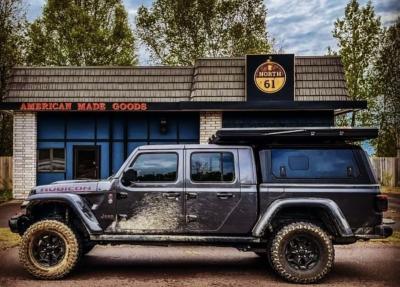 Photo of muddy vehicle with pop up tent parked in front of the North 61 store