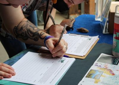 A close-up image of a person's hand as they sign a petition to support permanent Boundary Waters protections