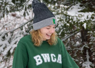 Photo of a person wearing a green BWCA crewneck sweatshirt and a Grey Winter Hat with an embroidered Minnesota on the front. 
