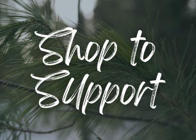 Pine needles with "Shop to Support" in white script font